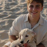 Person on the beach sitting with their dog